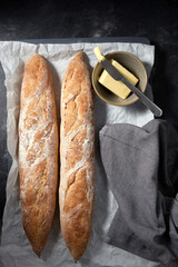 food, baking and cooking concept - close up of bread, butter in bowl and table knife on towel