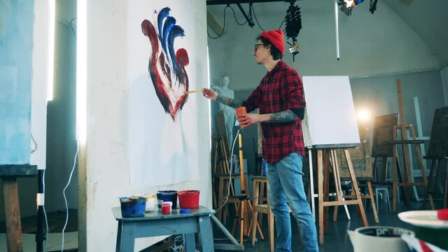 Male artist is creating a picture in his studio