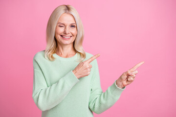 Photo portrait of woman blonde hair winking pointing finger blank space isolated on pastel pink...