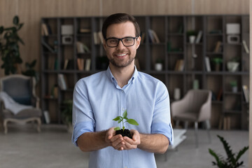 Portrait of smiling young businessman hold soil and small plant launch startup project or activity....