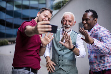  Three business men standing outside and using mobile phone. Focus is on background.