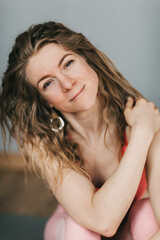 Fototapeta premium Portrait of a smiling girl in sports clothes, resting after a workout. Recreation, leisure, sports, yoga.