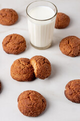 Freshly Homemade baked ginger cookies with cinnamon, sugar and glass of milk on light marble background. 