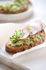 Fresh green spring sandwich with avocado and radish at light background. Copyspace