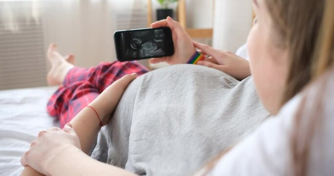 Two women looking at ultrasound image of future baby on smartphone
