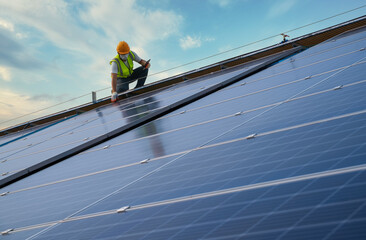 Engineer working on checking equipment in solar power plant. man working at solar roof paneled power station.engineers use tablet computer to examine solar panels installed solar panels using energy