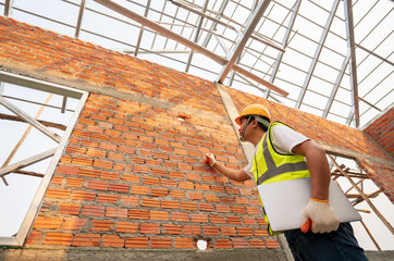 Engineering Consulting People on construction site holding notebook computer in his hand. Home building inspector. Construction site check drawing and business workflow of new structure building