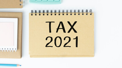White sheet with the text of the 2021 tax on the background and notepad.