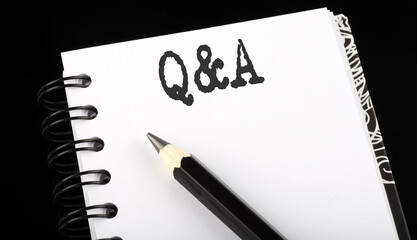 Q and A written text in a small notebook on a black background