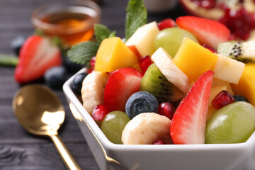 Delicious fresh fruit salad in bowl on table, closeup view