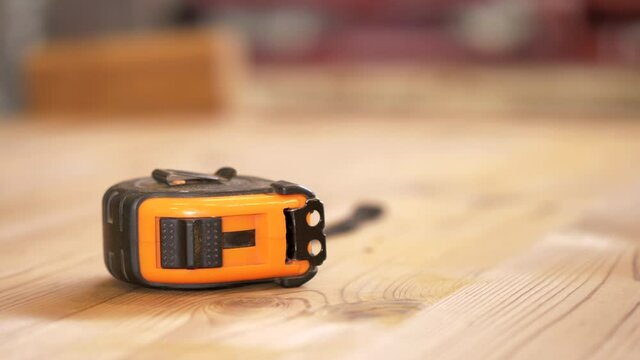 Carpenter tape measure on thermowood floor. dirty carpenter tool with small wood particles , super fine wood chips. Parallax