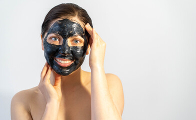 Woman relaxing with black charcoal facial mask