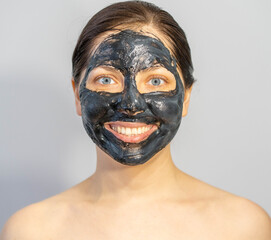 Woman relaxing with black charcoal facial mask