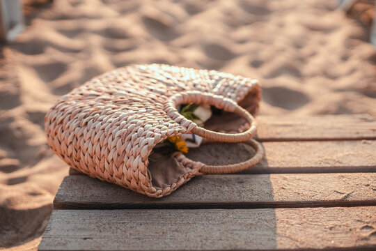 Traveling wicker straw bag on a wooden bridge near the sand beach. Resting at the resort.