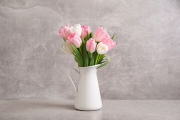 Beautiful bouquet of tulips in jug on light table