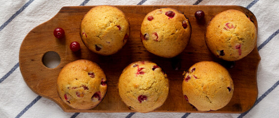 Homemade Cranberry Muffins with Orange Zest on a rustic wooden board on cloth, top view. Flat lay, overhead, from above.