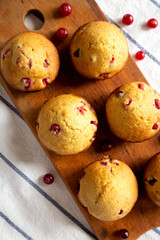 Homemade Cranberry Muffins with Orange Zest on a rustic wooden board on cloth, top view. Flat lay, overhead, from above.