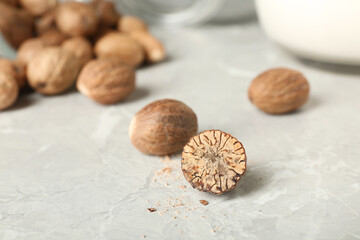 Whole and cut nutmeg seeds on light marble table