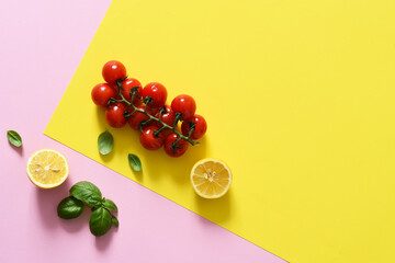 Lemon slice and bunch of cherry tomatoes on a yellow, pink background. Food trend concept.