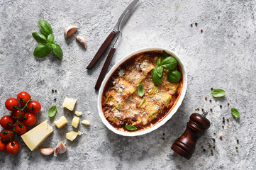 Baked zucchini rolls with ricotta cheese and tomato sauce and basil on a concrete table. View from above.