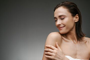 White brunette woman smiling while posing in bath towel