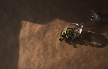 Dried leaves inside a glass which lies on a soft brown, craft background