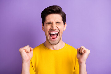 Photo of young excited crazy smiling cheerful positive man yelling hold fists in victory isolated on violet color background