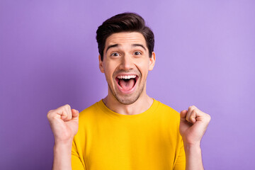 Photo of astonished guy fists up celebrate open mouth yell yeah isolated on pastel violet color background