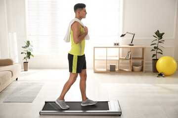 Fototapeta premium Sporty man training on walking treadmill at home