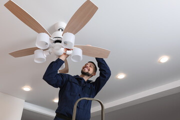 Fototapeta Electrician repairing ceiling fan with lamps indoors obraz