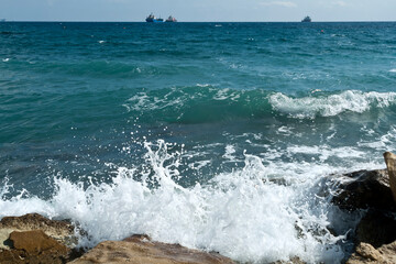 Splashing sea waves and ships on the horizon