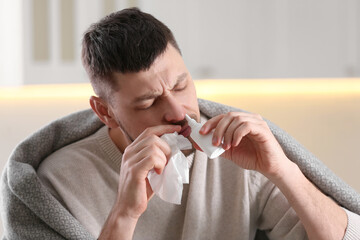 Ill man using nasal spray at home