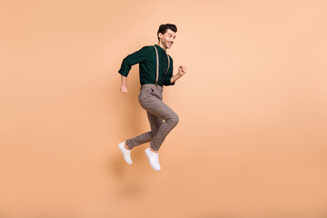 Fototapeta na wymiar Full length profile side photo of young man jump up run empty space sale hurry isolated on beige color background