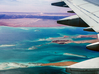 Fototapeta premium Aerial view above the clouds and sky, Inspiration concept. Travel freedom by air. Flight, view from the airplane to tropical sea with corals. Turbo-jet aircraft engine, transport. Passenger airbus