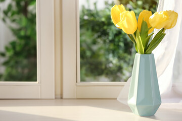 Beautiful fresh yellow tulips on window sill indoors. Spring flowers