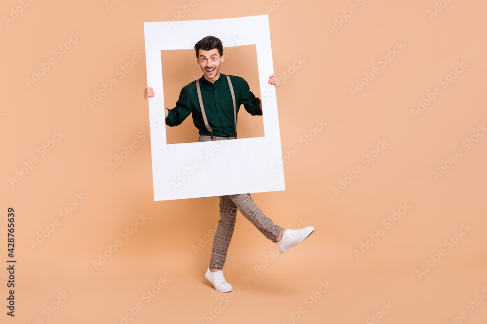 Sticker photo of funky guy hold retro picture frame dance wear green shirt suspenders footwear isolated beig