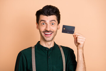 Photo of young smiling cheerful handsome man hold credit card online purchase isolated on pastel color background