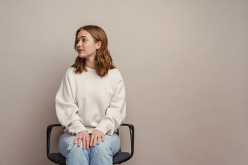 Young white woman looking aside while sitting on chair