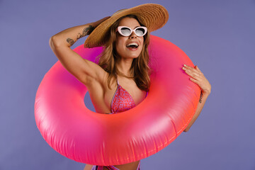 Young white woman in swimsuit and sunglasses holding rubber ring