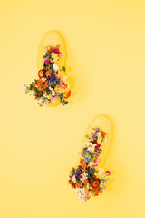 Yellow sneaker on a yellow background filled with flowers. Flat lay. Spring minimal abstract modern koncept.