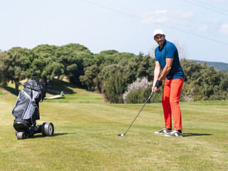 A young Caucasian male playing golf on a professional golf course