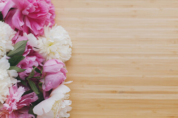 Peony bouquet on wooden background top view with space for text. Pink and white peonies flowers