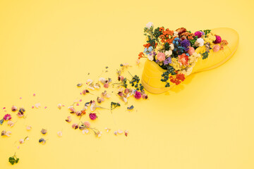 Yellow sneaker on a pastel blue background filled with flowers.  Spring minimal koncept.