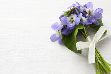 Beautiful wild violets and space for text on white wooden table, top view. Spring flowers