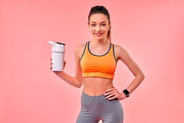 Cute athletic girl in sportswear with protein shake isolated on pink background. Sports, yoga,...