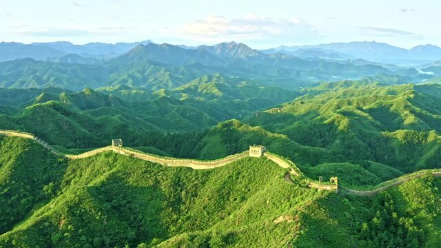 Aerial drone rotating shot, green mountains and Great Wall of China under sun