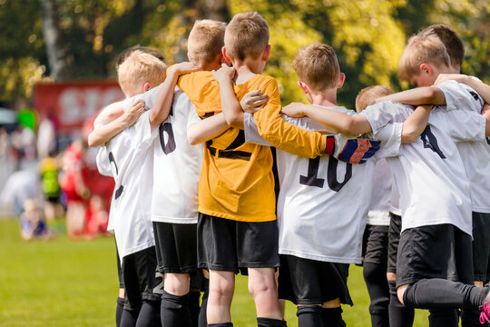 Group of happy sports boys huddling in a team. Happy school kids play sports together. Children motivating each other before playing a soccer football game. Sports Competition for Youth © matimix