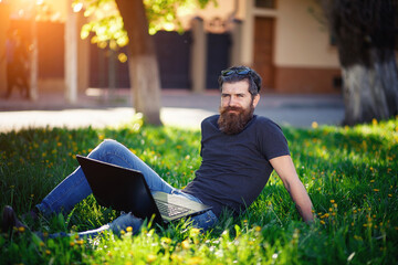 Charismatic bearded male software developer with a long mustache in a shirt and jeans sits with a...