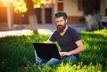 Charismatic bearded male software developer with a long mustache in a shirt and jeans sits with a...