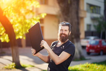 Cheerful bearded male programmer with a long beard and dark gray hair in a shirt and jeans waving a...